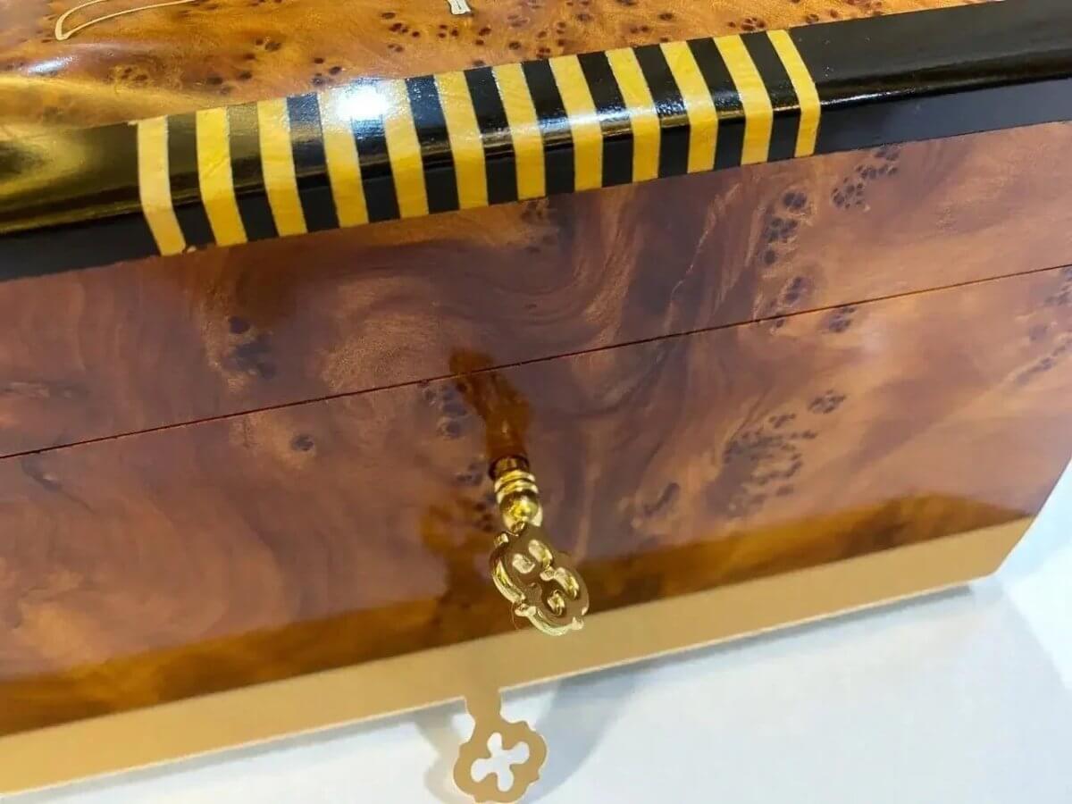 AtlasMuseCrafts handmade Moroccan Thuya wood jewelry box with swirling amber burl grain and gold key detail.