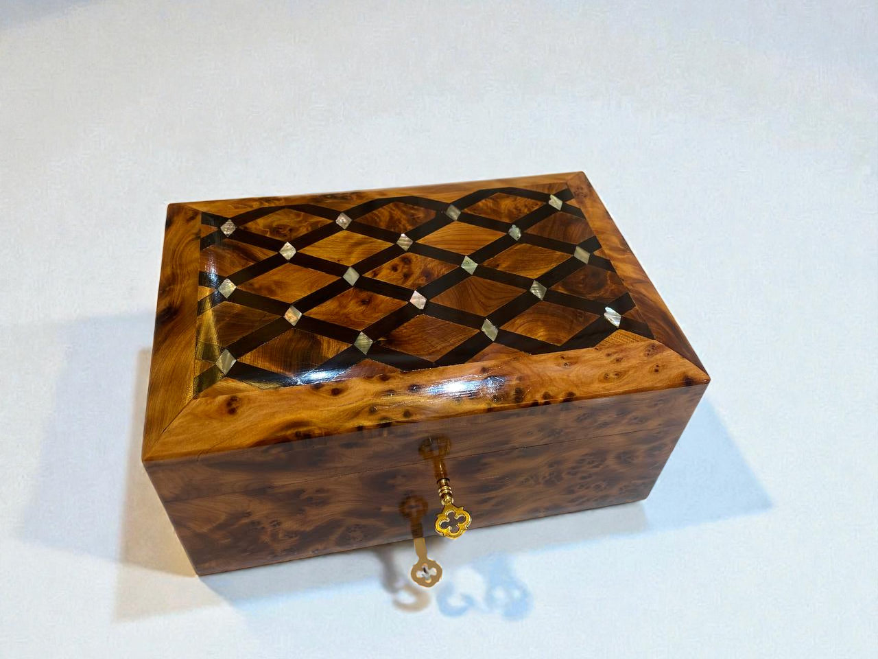 Wooden jewelry box with intricate design and key on a white background