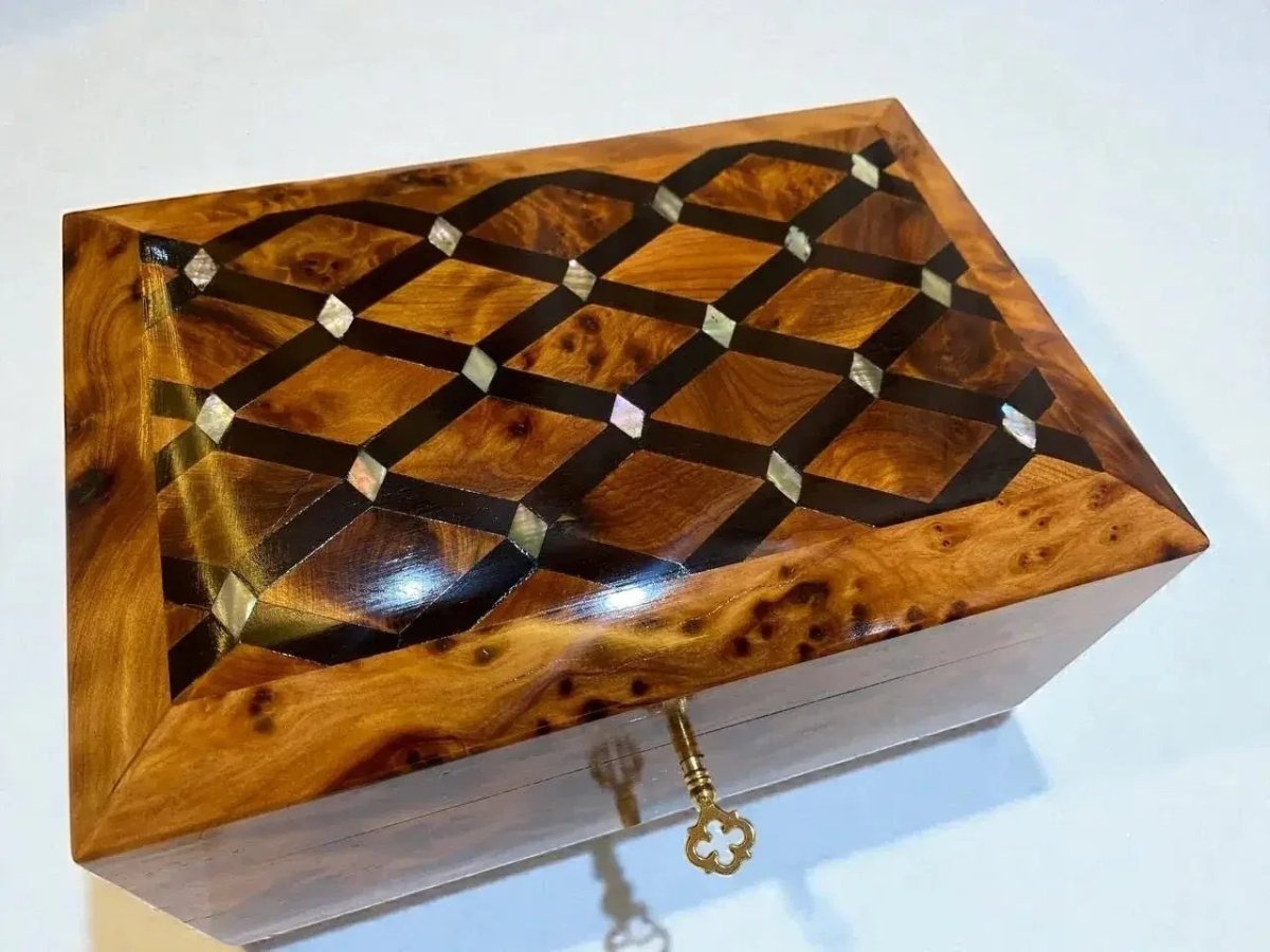 AtlasMuseCrafts handmade Thuya wood jewelry box with intricate geometric inlay of dark wood and mother-of-pearl accents. Features a warm amber burl wood grain and a decorative brass key.