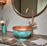 Pedestal green patina copper vessel sink showcased in a stylish bathroom setting with modern fixtures.