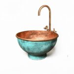 Pedestal green patina copper vessel sink displayed in a stylish bathroom with copper faucet and elegant decor.