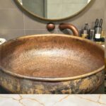 Hammered Copper Bathroom Sink showcased in a stylish bathroom with elegant decor and accessories.